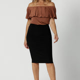 An off-the-shoulder top for summer, this slinky jersey top is a good top for over 40s style. Shown on a size 12 woman, this easy-care top is worn with a knee length, tube skirt. Made in Australia by Australian and New Zealand women's clothing brand, Leina & Fleur. Shop petite to plus size tops online for summer.