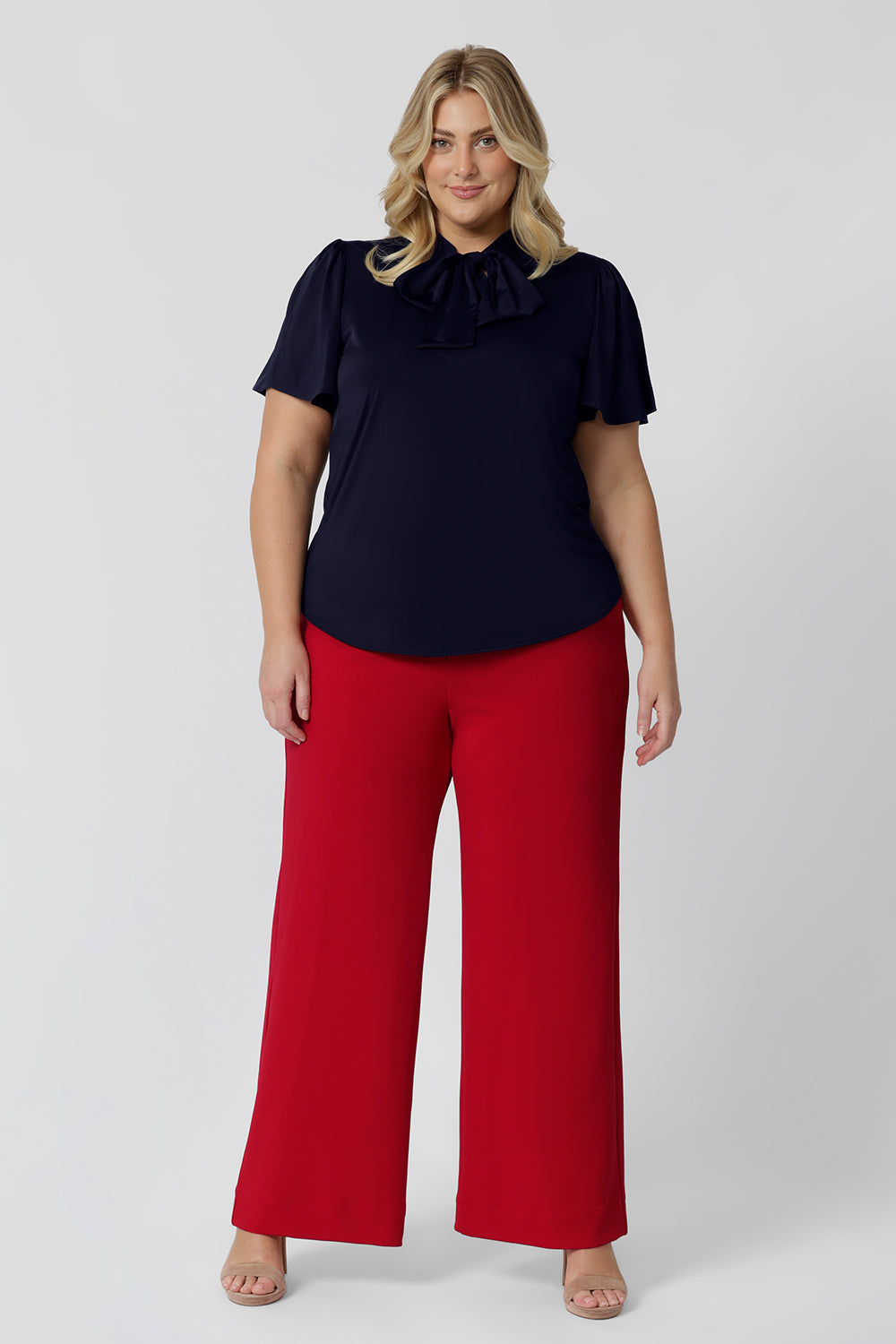 Showing good pants for plus size women, a size 18 woman wears high waisted wide leg trousers for curves in red stretch jersey. Made in Australia for by Australian-made fashion brand, Leina & Fleur. Stylish corporate wear for women. Made in Australia size 8 - 24.