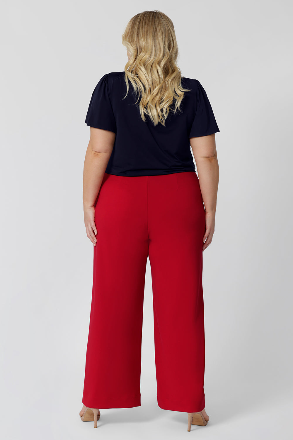 Back view of good pants for plus size women, a size 18 woman wears high waisted wide leg trousers for curvy women in red stretch jersey. Made in Australia for by Australian-made fashion brand, Leina & Fleur. Stylish corporate wear for women. Made in Australia size 8 - 24.