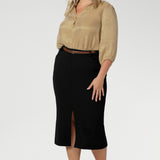 This stretchy, easy-care skirt is a perfect workwear piece for elevated suit styling with matching jacket or blazer. Size 18 model wears her midi length workwear skirt with brown kitten heels and a gold collared blouse.