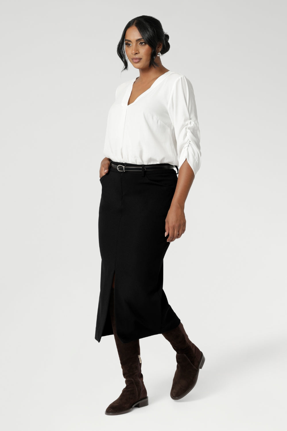 Image of Australian made black workwear skirt seen on over 30's woman paired with white blouse and brown boots for an elevated workwear look. Sizes 8-24 available at Leina & Fleur.