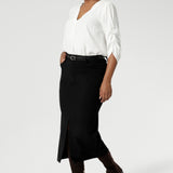 Image of Australian made black workwear skirt seen on over 30's woman paired with white blouse and brown boots for an elevated workwear look. Sizes 8-24 available at Leina & Fleur.