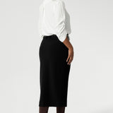 Back view image of Australian made black workwear skirt seen on over 30's woman paired with white blouse and brown boots for an elevated workwear look. Sizes 8-24 available at Leina & Fleur.