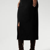 Close up image of Made in Australia by Australian and New Zealand women's clothing brand, Leina & Fleur. This stretchy, easy-care skirt is a perfect workwear piece for elevated suit styling with matching jacket or blazer. Size 10 model wears her midi length workwear skirt with long boots and a white collared blouse.