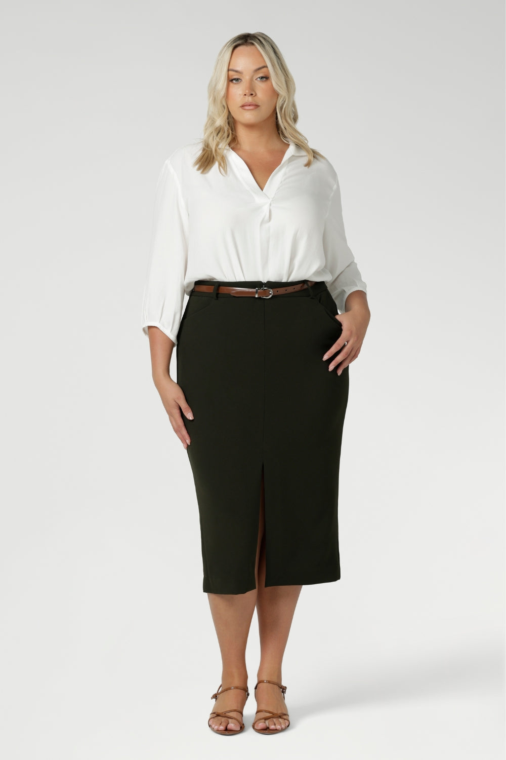 Plus size woman wears Australian made Olive workwear skirt seen on plus size woman paired with white blouse and brown kitten heels for an elevated workwear look. Sizes 8-24 available at Leina & Fleur.