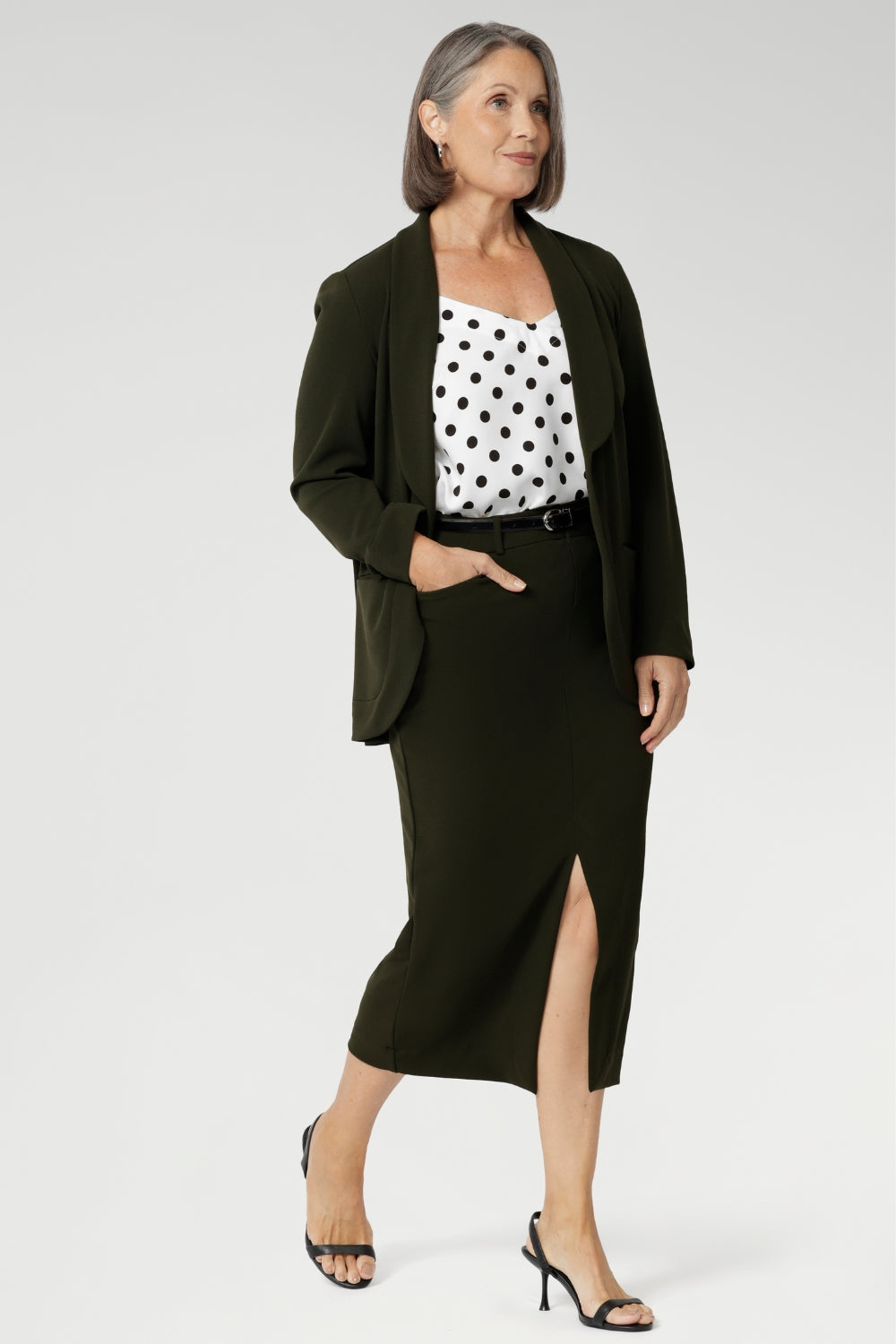 Womans easy care midi skirt made from Scuba crepe jersey fabric. Crafted with functional patch pockets, tailored shawl collar and covered front button. Woman's blazer will have you looking stylish in all corporate and casual occasions. Woman's workwear clothing made in Australia sizes 8-24. Size 10 woman wears her olive coloured midi skirt with matching Olive Blazer and black & white blouse.