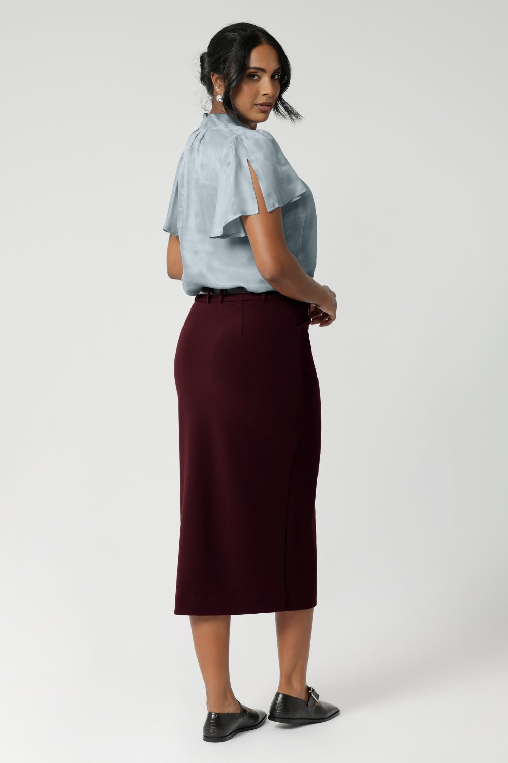 Back darts enhance the skirt’s shape, providing a tailored silhouette. The midi-length design offers a modern and flattering fit, making it a perfect choice for professional or dressy occasions.