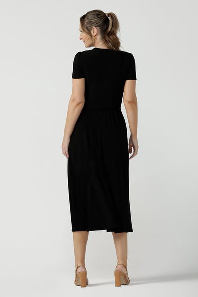 Back view of size inclusive jersey wrap dress in size 8. Curvy women workwear midi dress with pockets. Black dress. 