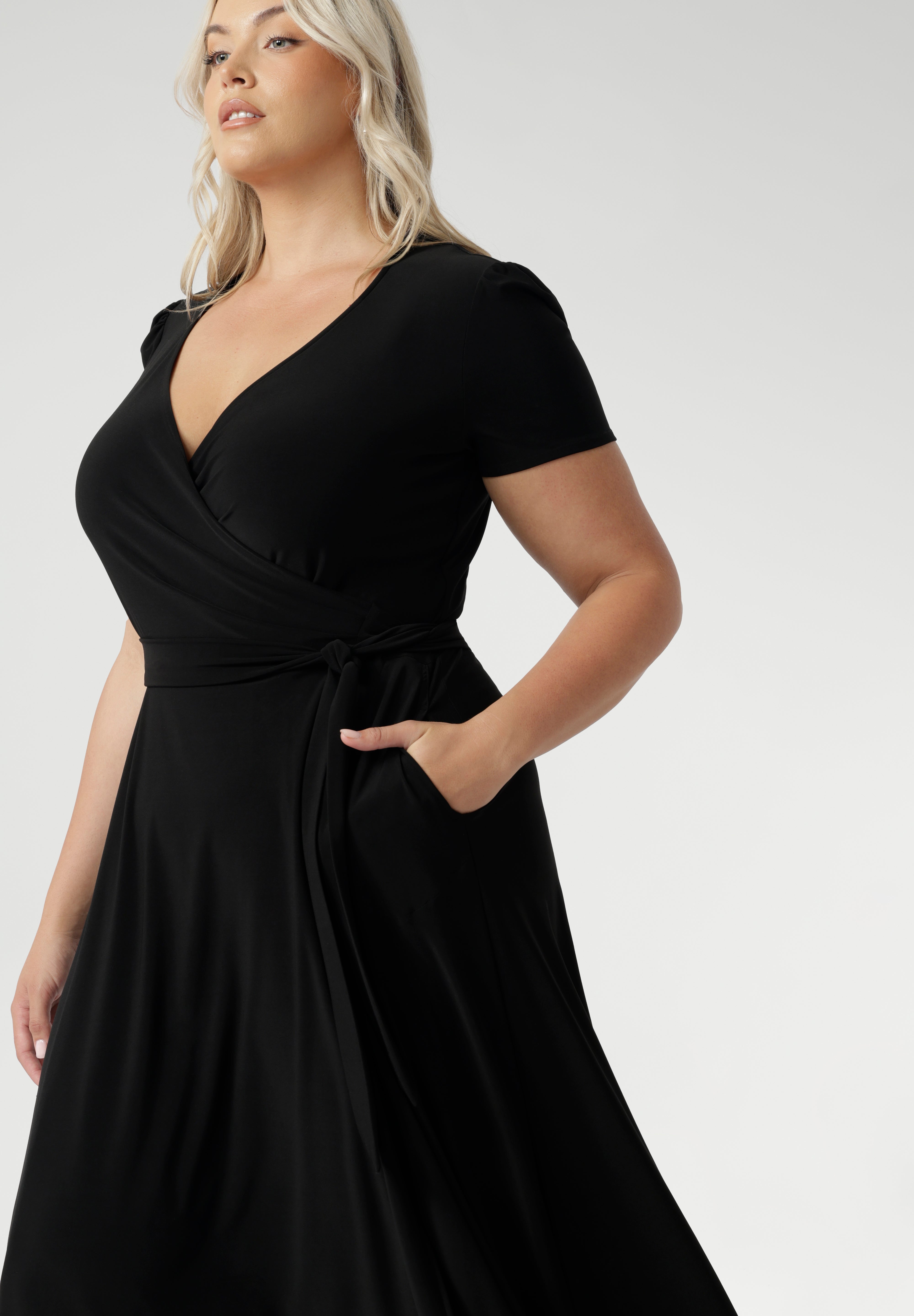 The functioning wrap design features an elegant double-layer back bodice and extended waist ties for a flattering fit. Short sleeves with tucks at the sleeveheads add a touch of detail, while the A-line skirt enhances its feminine silhouette. With side pockets for added practicality, this midi-length dress is an ideal choice for curvy women seeking stylish workwear. Available in sizes 8-24, the Alexis dress is the perfect plus-size wrap dress for women looking for a flattering, functional, and fashionable