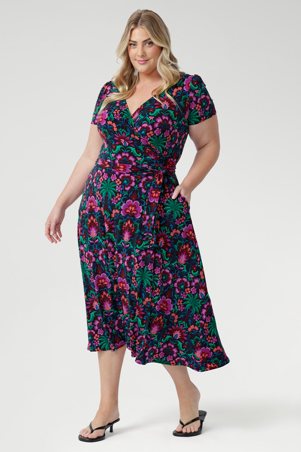 The fully functioning wrap style includes extended waist ties for a customisable fit, while the double-layer back bodice offers added comfort and structure. Thoughtful details like gathered sleeve heads, an A-line skirt, and practical side pockets enhance both style and functionality.