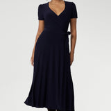 A curvy, size 18 woman wearing a navy, wrap dress with short sleeves. A great dress for summer casual wear, or for travel. Shop made in Australia dresses in petite to plus sizes online at Australian fashion brand, Leina & Fleur.