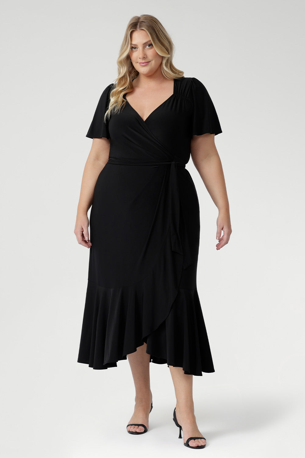 Luxe Alita Wrap Dress in Black with soft sheen fabric, flattering ruching, and deep ruffle hem for an elevated evening look.