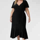 Luxe Alita Wrap Dress in Black with soft sheen fabric, flattering ruching, and deep ruffle hem for an elevated evening look.