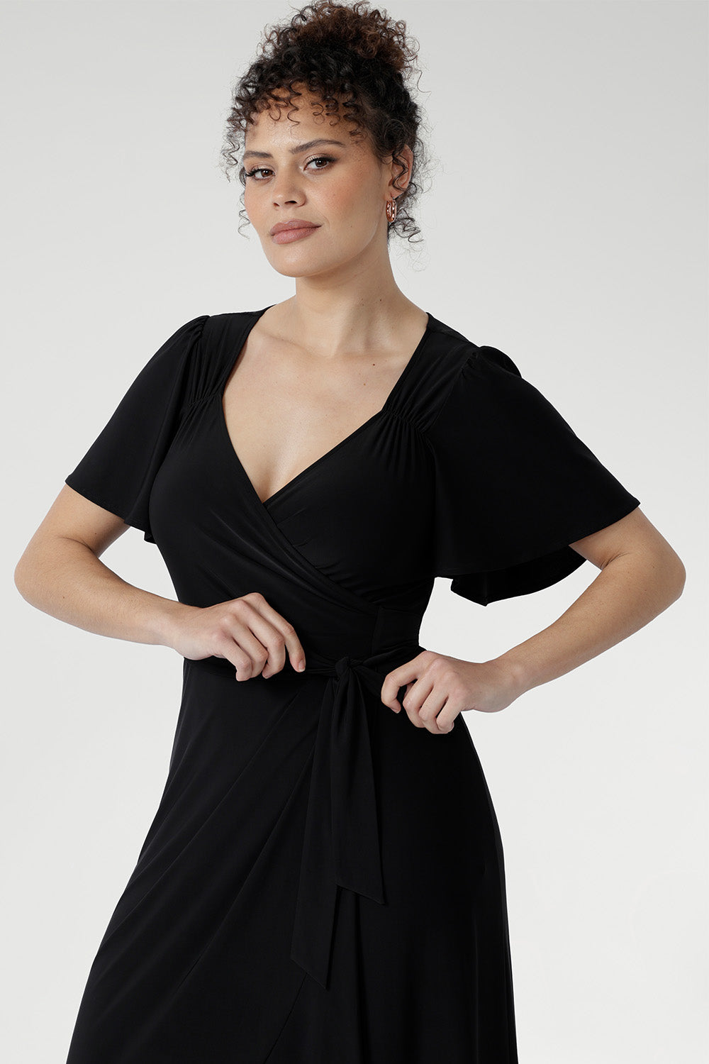 Glamorous Alita Black Wrap Dress with sheen finish, deep hem ruffle, and flattering wrap silhouette for special occasions.