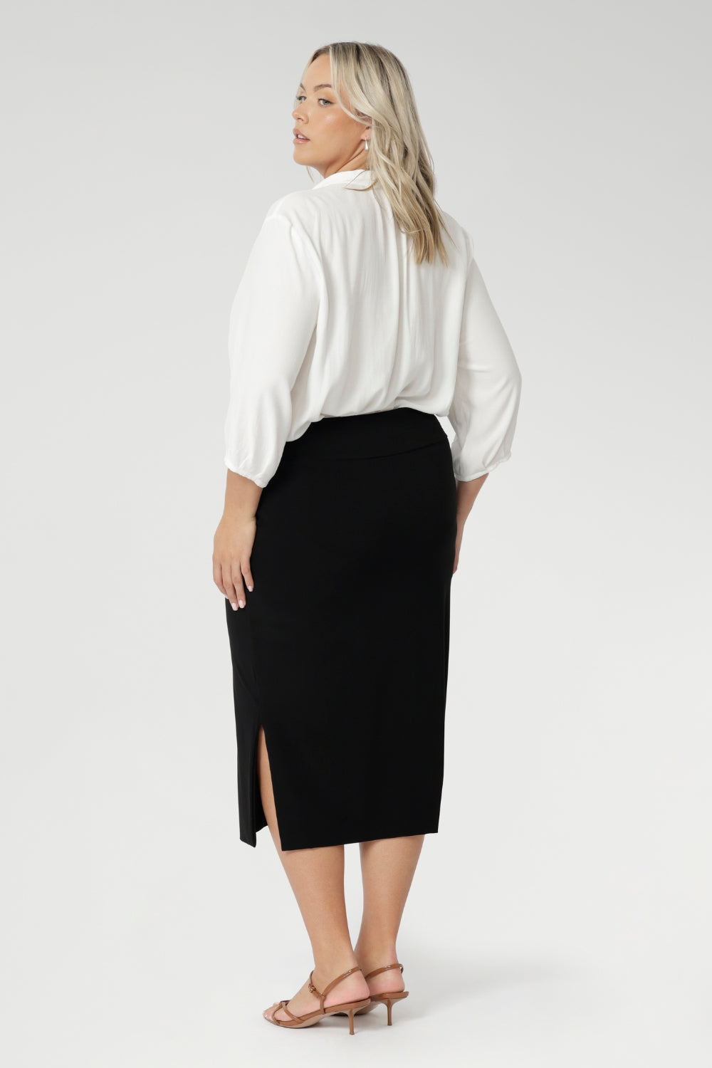 Size 18 woman wears Andi Midi Skirt in Black is designed in a sophisticated mid-calf length with a flattering side-split, making it perfect for both work and events.