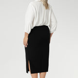Size 18 woman wears Andi Midi Skirt in Black is designed in a sophisticated mid-calf length with a flattering side-split, making it perfect for both work and events.