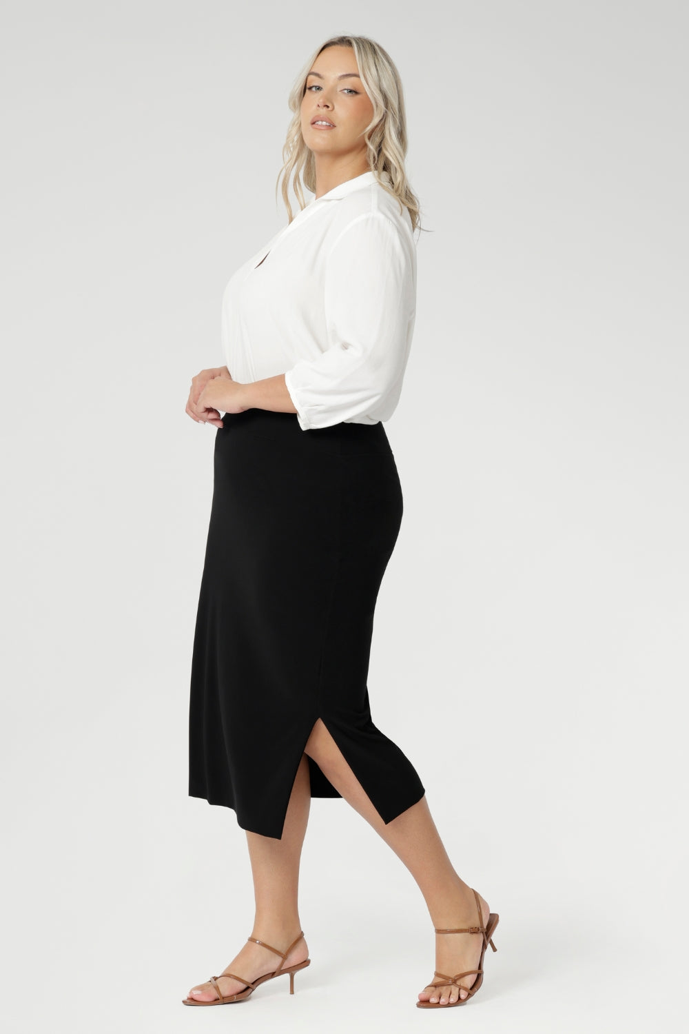 Size 18 woman wears Andi Midi Skirt in Black is designed in a sophisticated mid-calf length with a flattering side-split, making it perfect for both work and events.