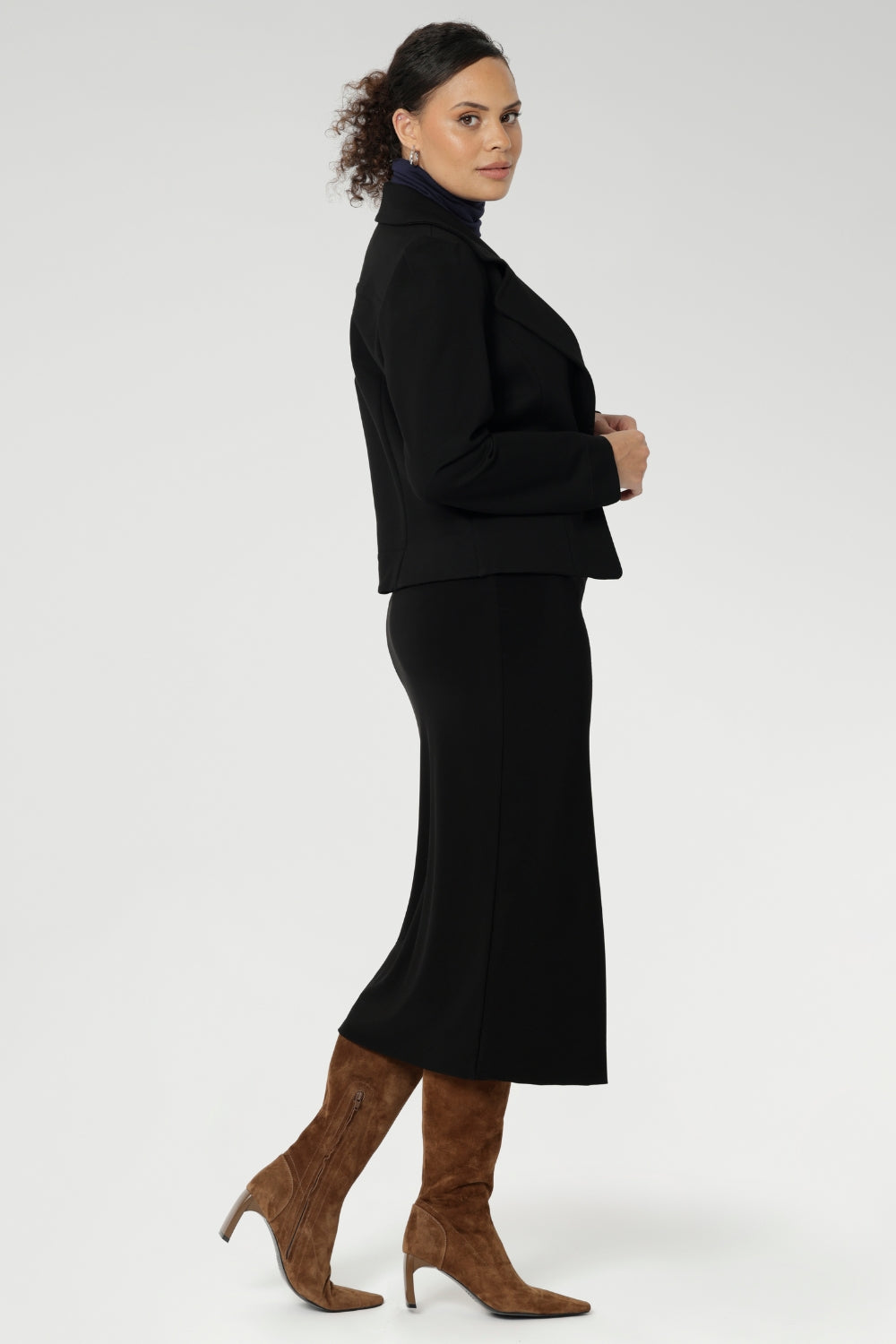The Andi Midi Skirt in Black is designed in a sophisticated mid-calf length with a flattering side-split, making it perfect for both work and events. Crafted as a double-layer tube skirt, it features a soft folded waistband and a comfortable pull-on style, combining elegance with ease of wear.