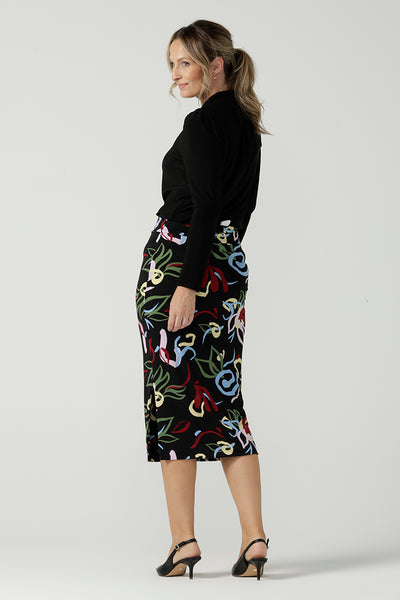 A size 10 woman wears the Boronia Midi Skirt back with a black tie neck top. Made in Australia for women size 8 - 24.