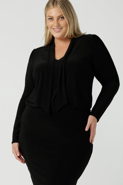 Size 18 woman wears the Thom top in Black a tie neck top with a V-neckline. Made in comfortable jersey have and made in Australia for women size 8 - 24. 