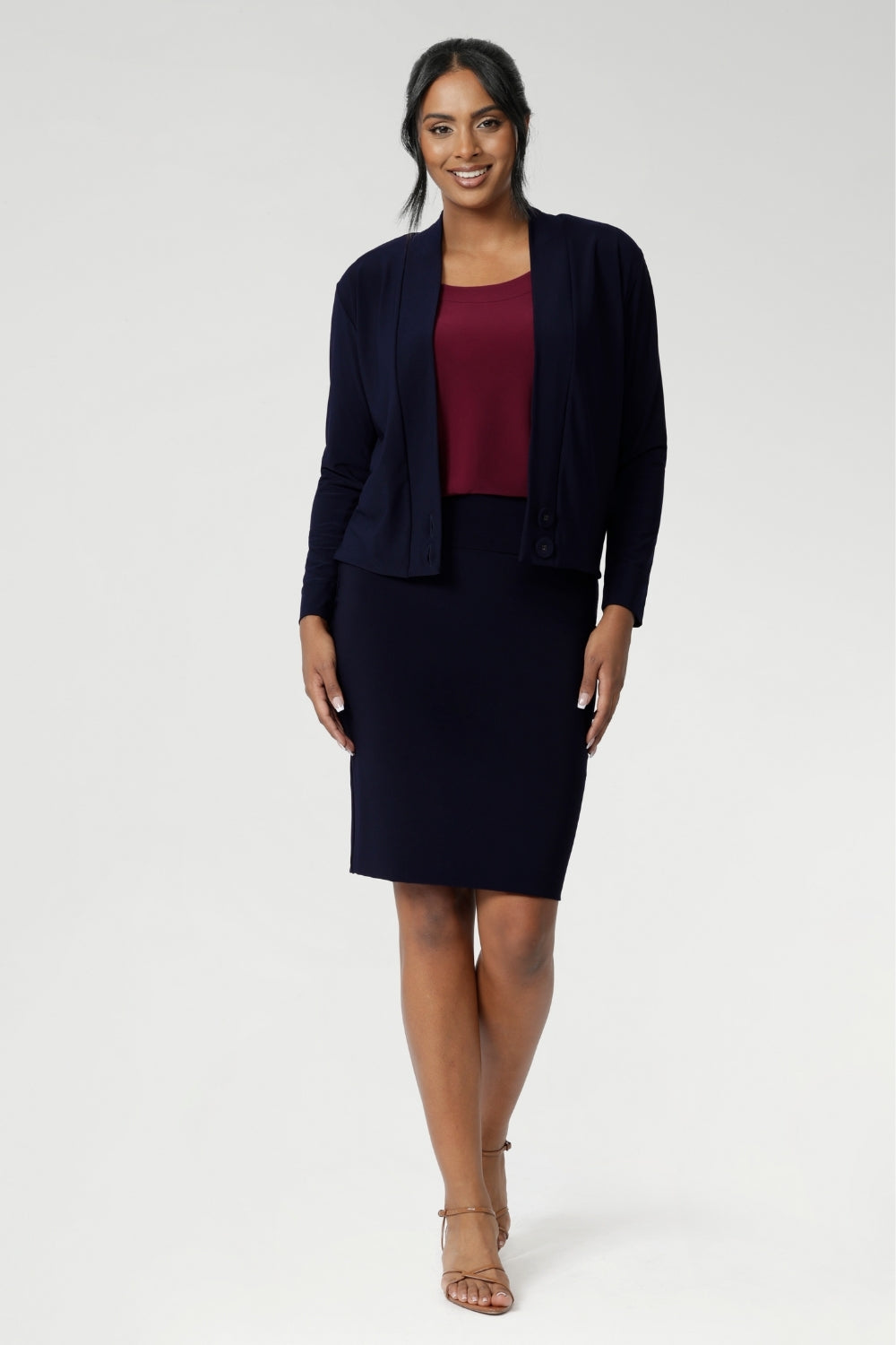 The Andi Tube Skirt is available in a mini, regular and midi length for a bold and stylish look no matter your style. Size 10 woman wears her navy tube skirt with matching jacardi in navy & ruby Top.