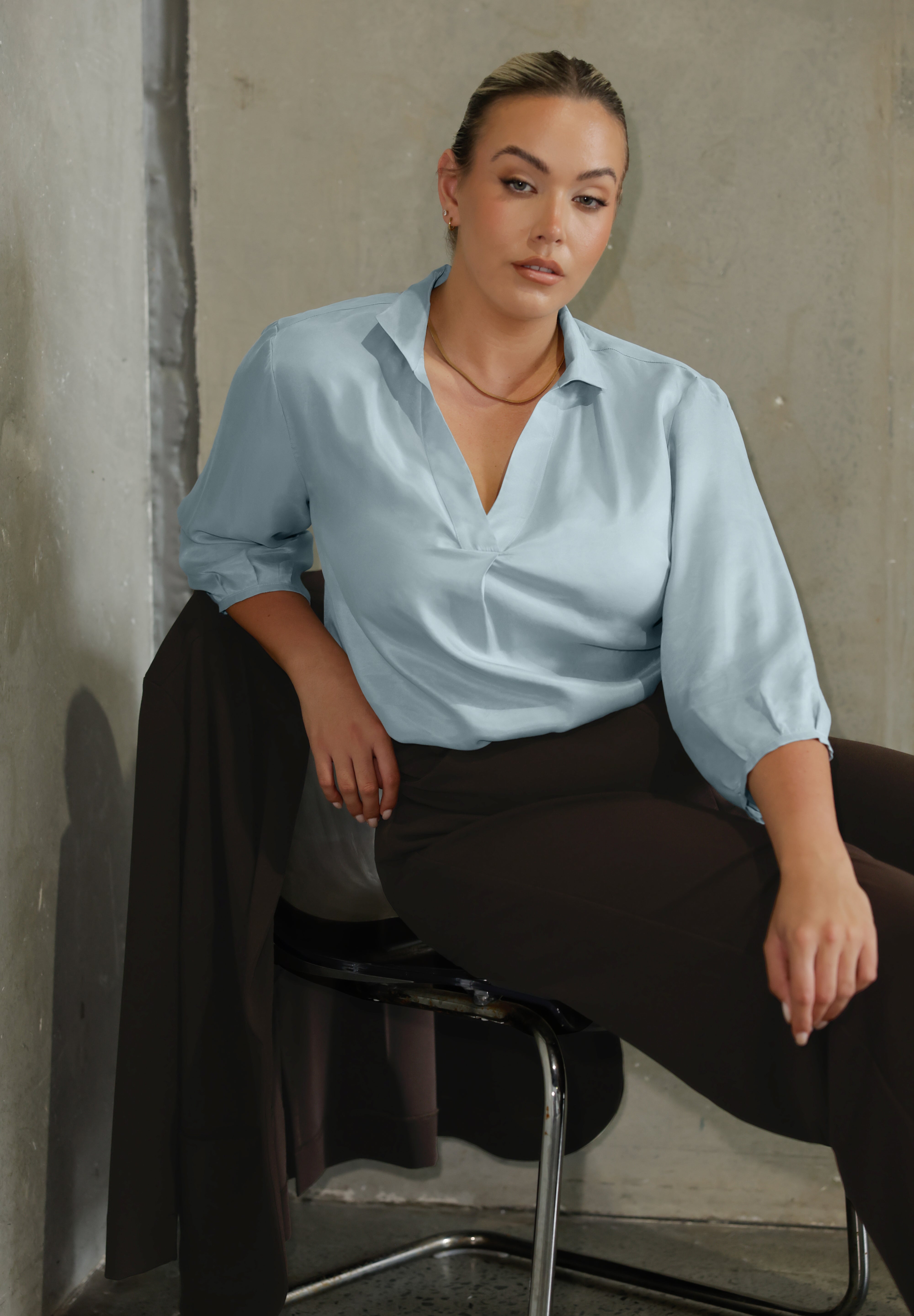 This pull-on style combines a sleek, contemporary silhouette with thoughtful detailing, making it a go-to piece for effortless polish. Semi-fitted through the body, it features a classic collar neckline and subtle tuck details below the back neckline, adding gentle structure without compromising comfort. The ¾ length sleeves fall softly and are finished with narrow bound hems, bringing a refined finish to a relaxed shape. A curved shirttail hemline completes the look.