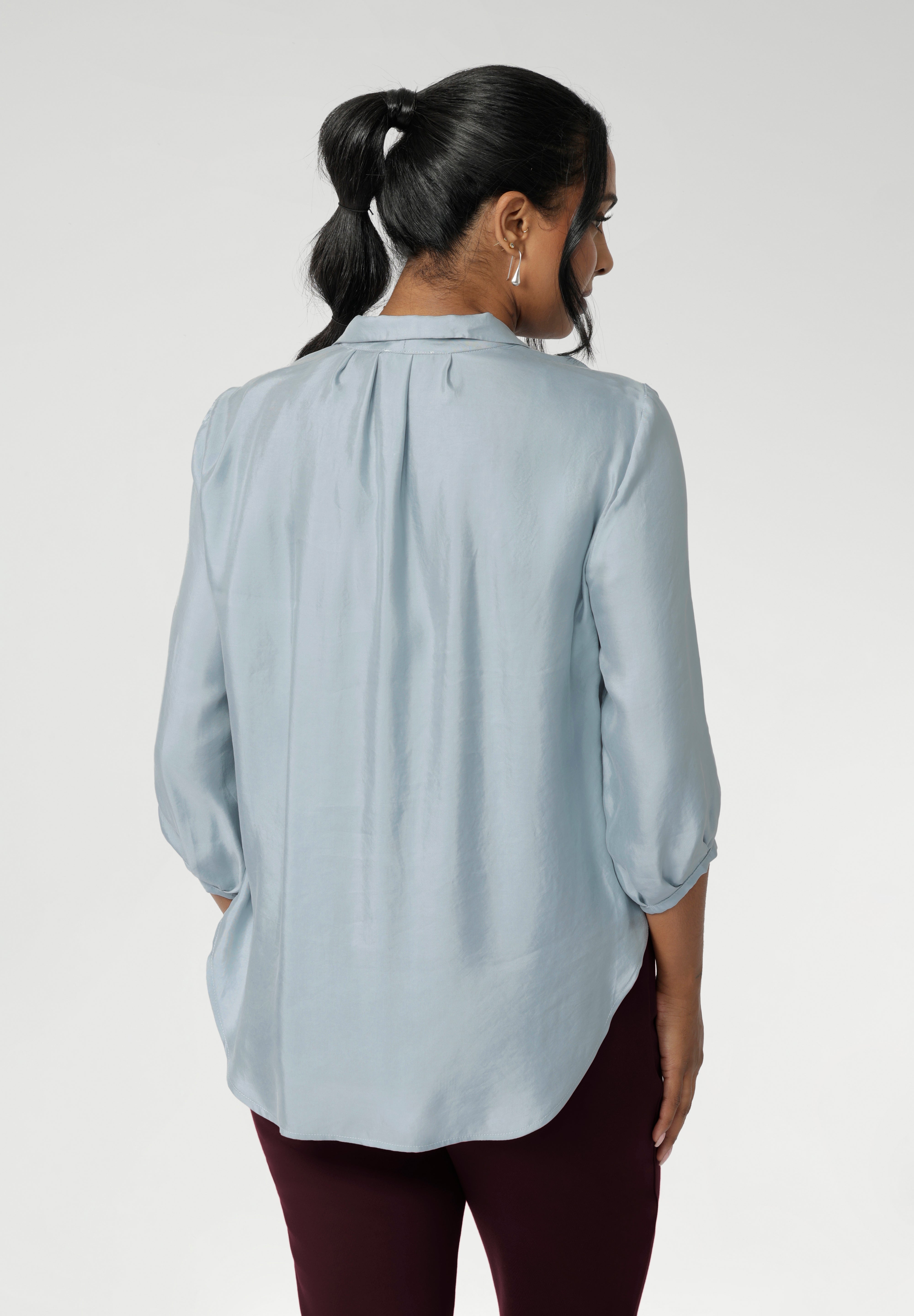 Semi-fitted through the body, it features a classic collar neckline and subtle tuck details below the back neckline, adding gentle structure without compromising comfort. The ¾ length sleeves fall softly and are finished with narrow bound hems, bringing a refined finish to a relaxed shape.