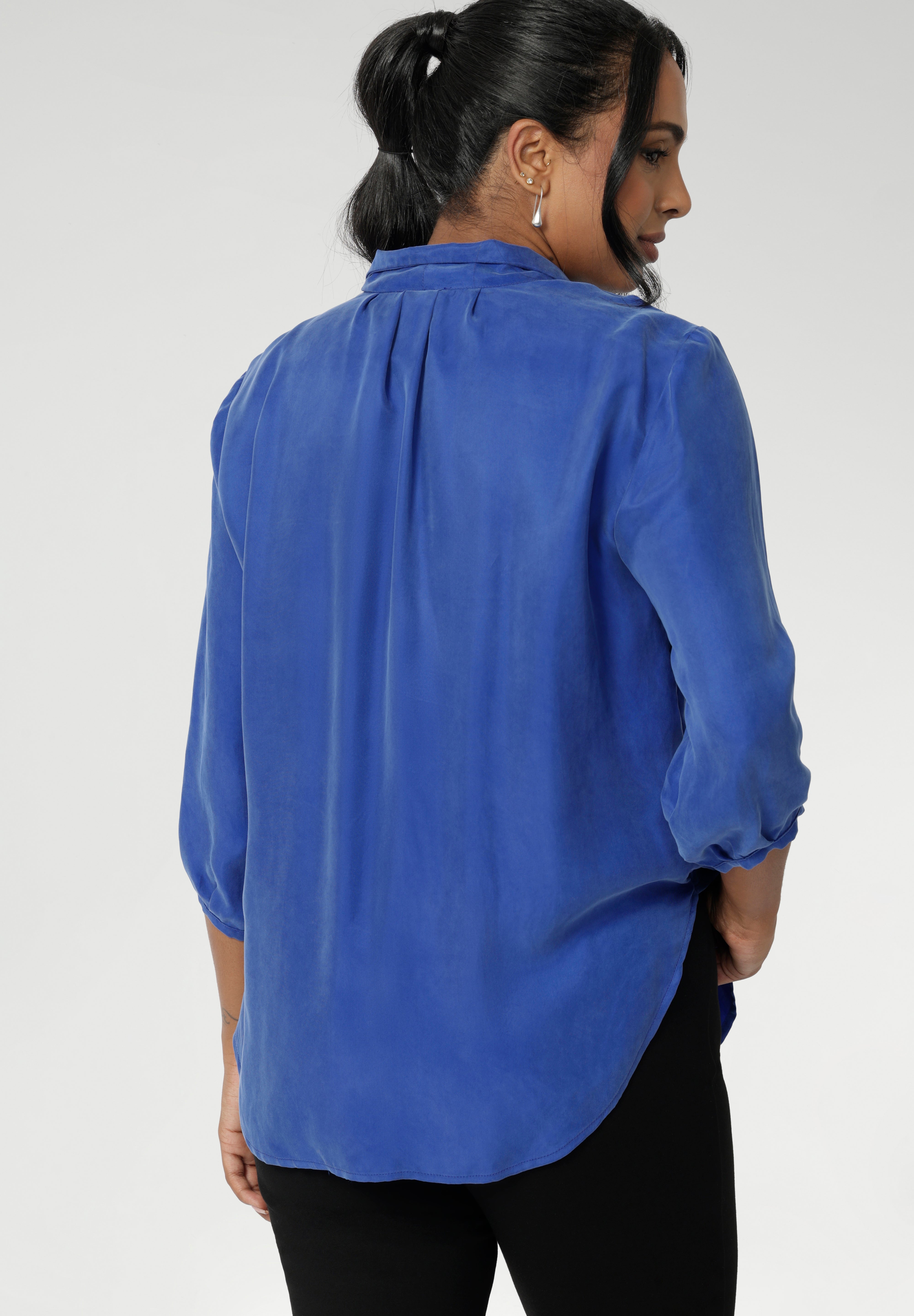 The semi-fitted shape creates a flattering line through the body, while the classic collar adds a sharp, structured touch. Soft tuck detailing below the back neckline introduces gentle shape and subtle interest, complemented by ¾ length sleeves with neatly bound hems for a polished finish.