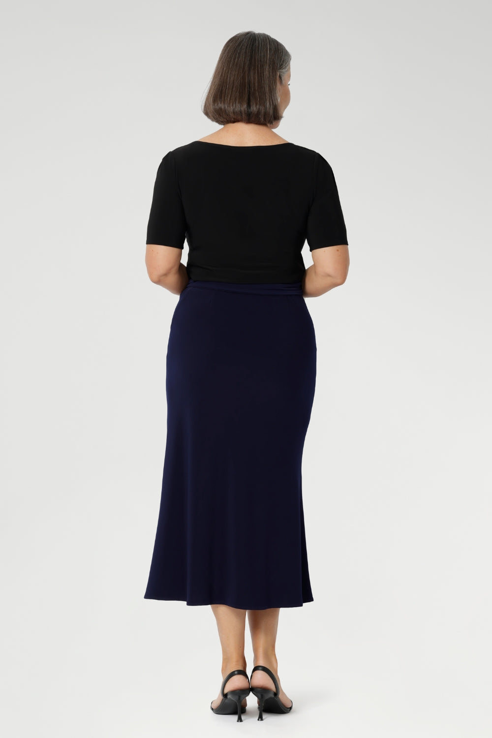 Made from dry-touch jersey fabric with soft stretch, it features a bias-cut design that creates a smooth, flowing silhouette. Mature aged model wears her Asher skirt in Navy with Black work top & Navy belt.