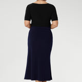 Made from dry-touch jersey fabric with soft stretch, it features a bias-cut design that creates a smooth, flowing silhouette. Mature aged model wears her Asher skirt in Navy with Black work top & Navy belt.