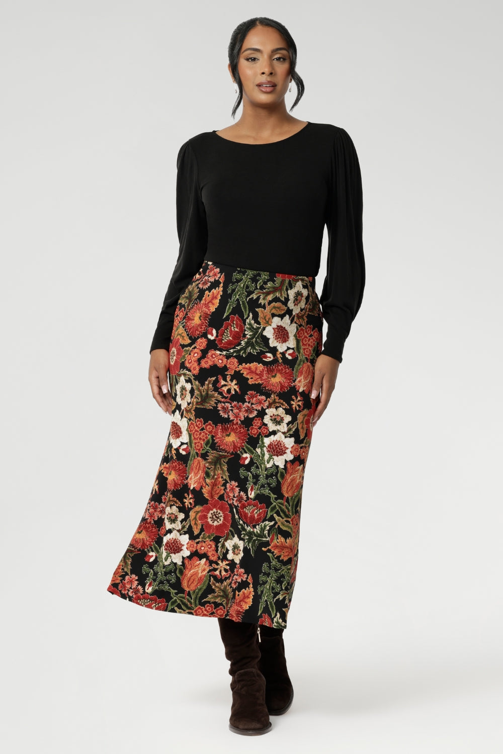 Designed with a modern, feminine cut, it features a boat neckline and full-length bellow sleeves. Size 10 woman wears her Knit Top with a floral printed skirt.