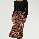 Designed with a modern, feminine cut, it features a boat neckline and full-length bellow sleeves. Size 10 woman wears her Knit Top with a floral printed skirt.