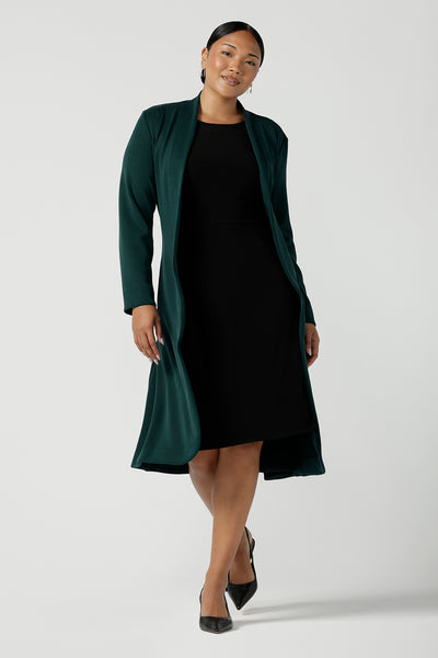 Green Sorel coast in a size 10 woman wears the Audrey Dress, a black jersey round neckline dress with pockets and a boat neckline. Knee length style and easy care workwear for women. Made in Australia for women size 8 - 24.
