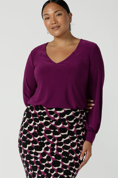 A size 10 woman wears the Avery top in Magenta, a long sleeve top with balloon sleeves and cuff detail. Soft v-neeckline and gathered back yoke. Made in Australia for women size 8 - 24. 