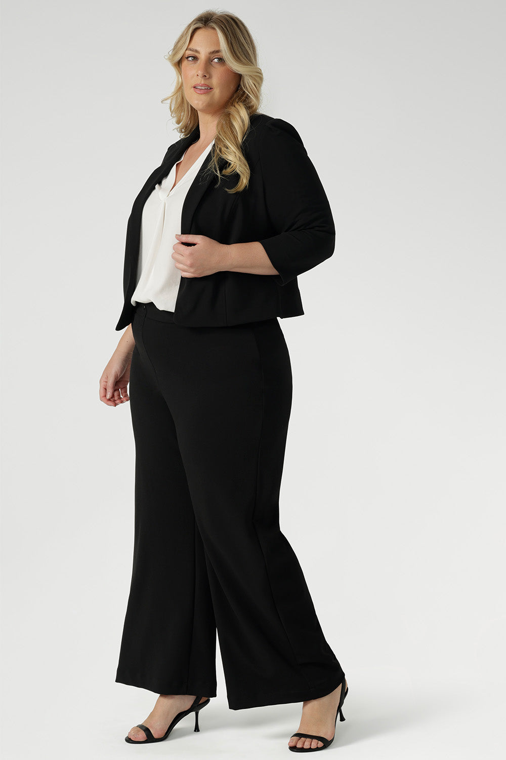 Size 18 woman wears black jacket that contours to the body for a flattering shape. 3/4 length sleeves with tucks at the sleeve heads add a unique, sophisticated detail that sets the jacket apart from traditional blazers