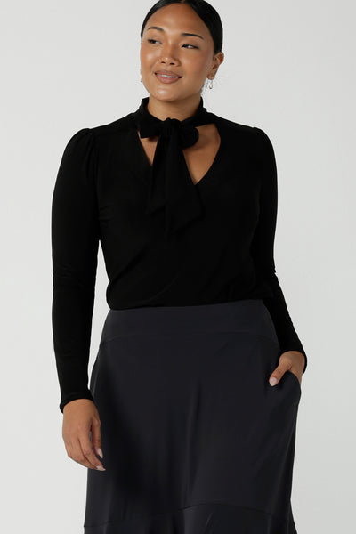 A size 12 woman wears the Thom top in Black a tie neck top with a V-neckline. Made in comfortable jersey have and made in Australia for women size 8 - 24.