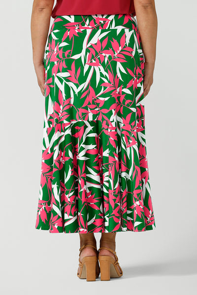 Back view up of a woman wearing a green jersey skirt with a leaf print. On a verdant green base in a soft jersey fabric. Made in Australia for women size 8 - 24.
