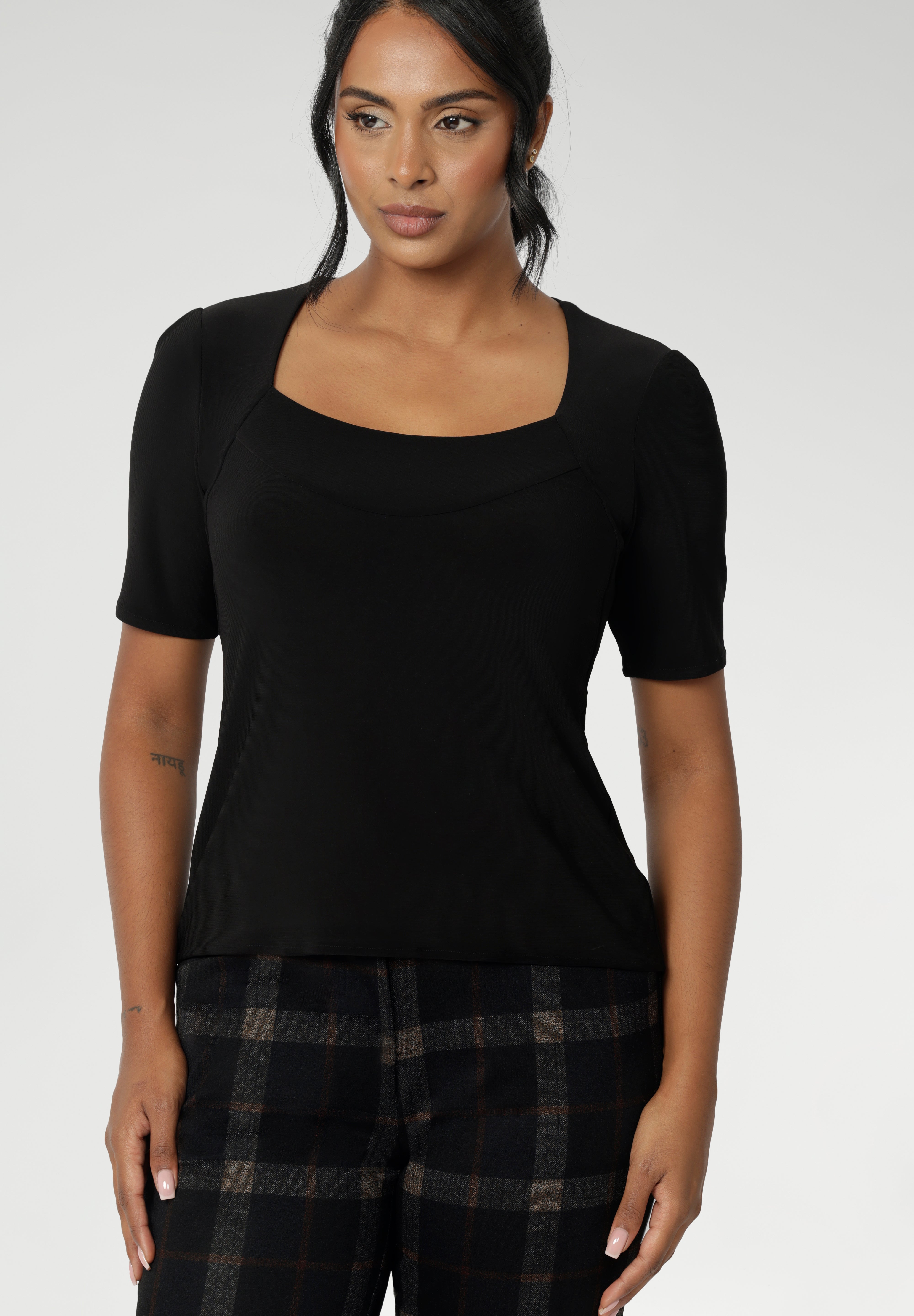 Over 30's woman wears short sleeve black top with square neckline. A slim fit top in classic black, this tailored jersey top wears well with workwear separates for an office look and also as a smart casual top. Shop tops online at Australian women's clothing brand, Leina & Fleur in sizes 8-24.