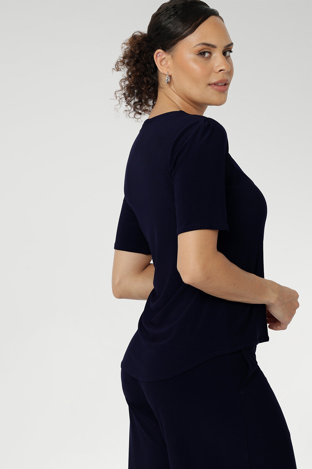 Size 10 woman wears a casual jersey top in navy blue. This Australian-made women's top has short fitted sleeves, a square neckline and and high-low - perfect for weekend casual and travel capsule wardrobes. Available in sizes 8-24.