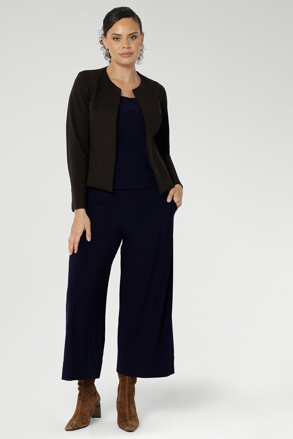Size 10 woman wears a casual jersey top in navy blue. This Australian-made women's top has short fitted sleeves, a square neckline and and high-low - perfect for weekend casual and travel capsule wardrobes. Available in sizes 8-24. Styled with matching navy culottes & brown jacket