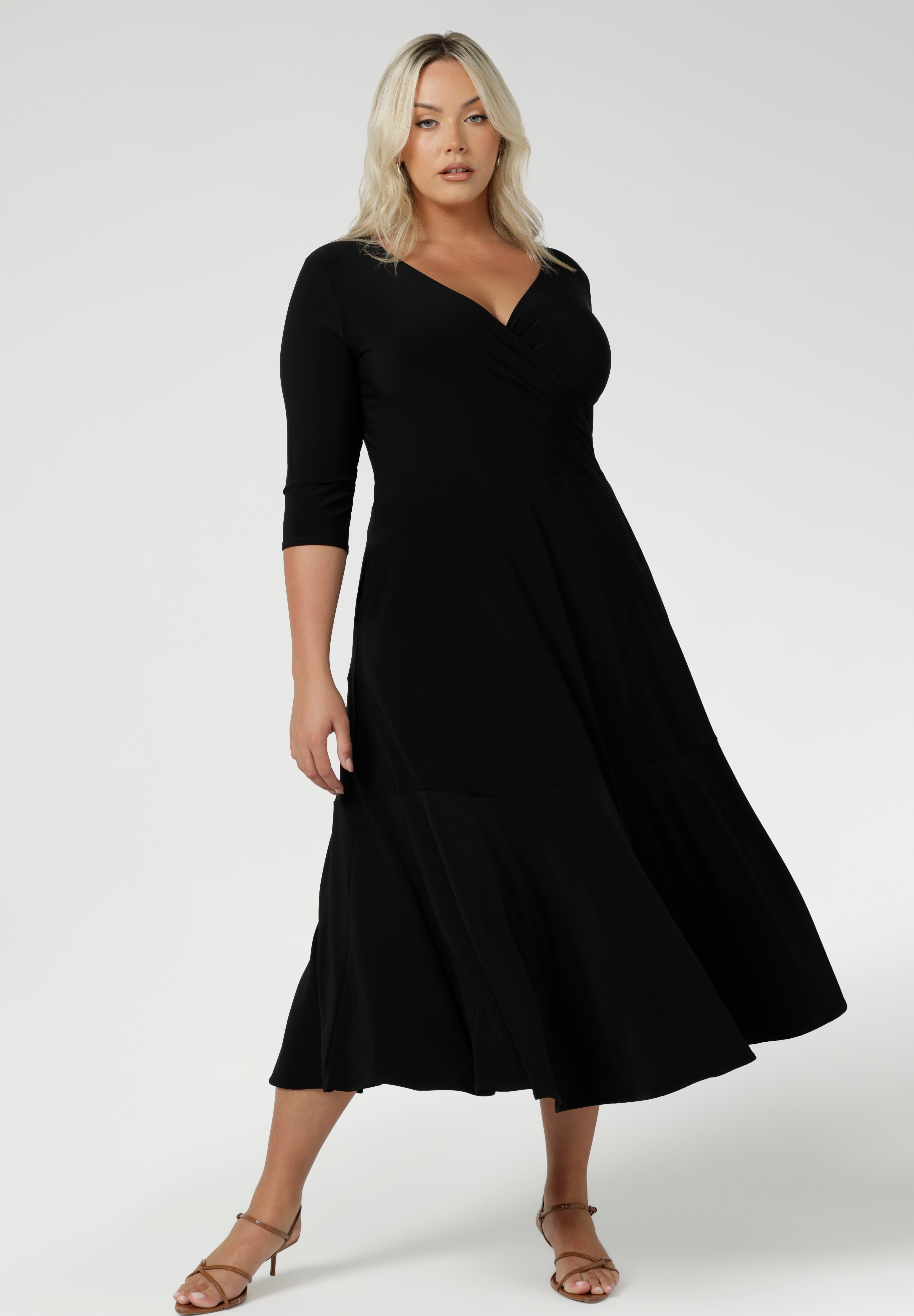 Size 18 woman wears a black reversible Bettina dress in black Jersey dress made in Australia. V-neck style with pockets and midi length. Made in Australia for women size 8 - 24. Reversible dress can be worn featuring boat neck or neck.