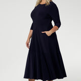 Close up of a size 18 woman wears a Bettina Reversible dress in Navy. Stylish workwear for women. Midi length with functional pockets. Made in Australia for women size 8 - 24. Soft Navy jersey fabric.