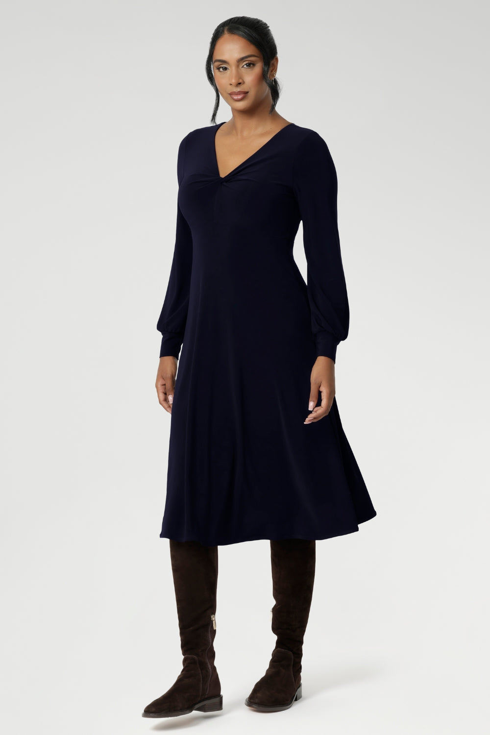 The Bianca Dress in Navy is a timeless black knee-length style designed for both work and special occasions. Featuring a sophisticated V-neckline with a twist-front bodice and cuffed long sleeves, it creates a flattering silhouette with elegant detail.