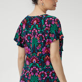 Thoughtful details like the centre-front pleat, raglan shoulders, short flutter sleeves, and a curved shirt-tail hemline create a beautifully balanced silhouette that suits a variety of body shapes.