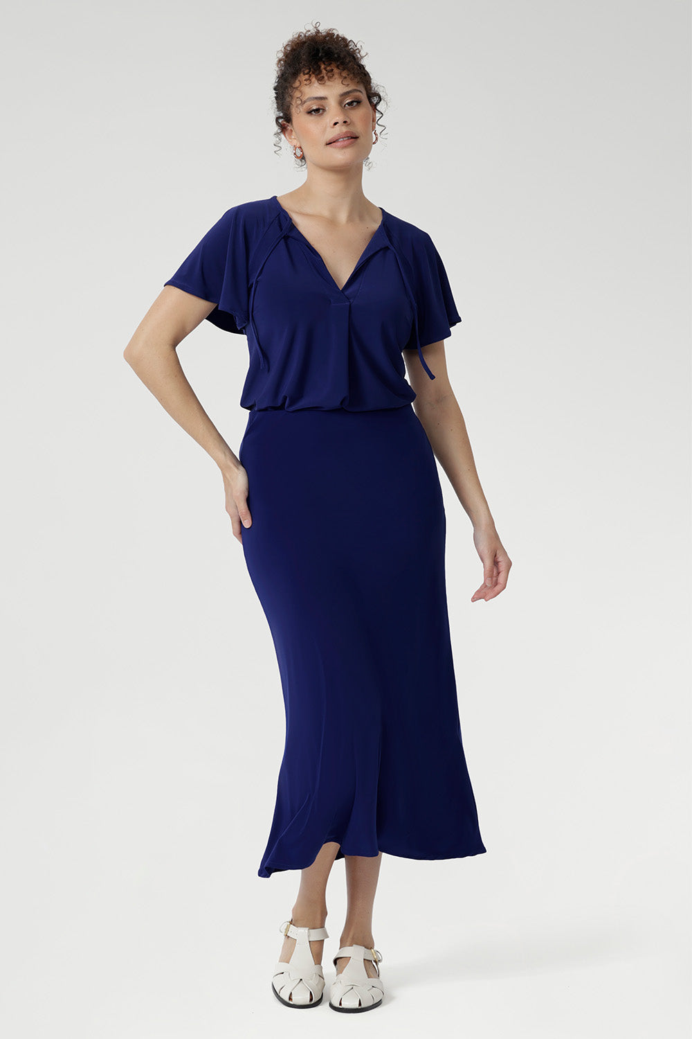 In a rich Sapphire hue, the Bowie Top is where effortless elegance meets everyday ease. Cut from dry-touch jersey with a hint of stretch, it features a fluid fit, refined pleats, and delicate ties. Flutter sleeves and a shirttail hem lend soft movement—ideal for both polished and casual moments.