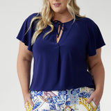 The Bowie Top in Sapphire brings relaxed sophistication to your wardrobe. Crafted from soft-stretch, dry-touch jersey, it features a V-neckline, pleat detail, and tie accents. With flutter sleeves and a shirttail hem, it’s an easy piece for office days or weekend plans.