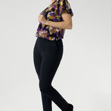 The vibrant painterly-style floral print, bursting with rich purples and soft yellow hues, brings a fresh pop of colour to any outfit. With its relaxed fit, centre-front pleat, raglan shoulders, and soft flutter sleeves, the Bowie Top drapes beautifully on the body, finished with a curved shirt-tail hemline for added movement.