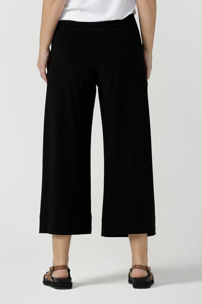 Back view of comfortable, wide leg black culotte pants worn with a V-neck white bamboo jersey top with short sleeves.. Cropped pants with pockets, these pull-on trousers are made in Australia by women's clothing brand, Leina & Fleur - size inclusive, shop online in petite, mid size and plus sizes.