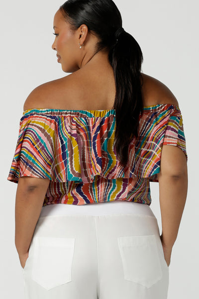 Back view of a size 16 woman wears an off shoulder top in vibrant rainbow swirl Briar top in soft slinky jersey. Made in Australia for women size 8 - 24.