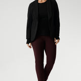 Size 10 woman wears knit top under black work wear blazer. Designed for comfort and versatility, it features a flattering close-to-body fit that moves with you, thanks to its generous stretch and breathable finish. Black knit top has thumbholes that can be used or tucked away for versatility in styling and extra warmth. Available in size 8-24.